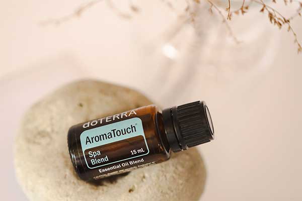 A doTERRA AromaTouch essential oil blend resting on a smooth spa stone